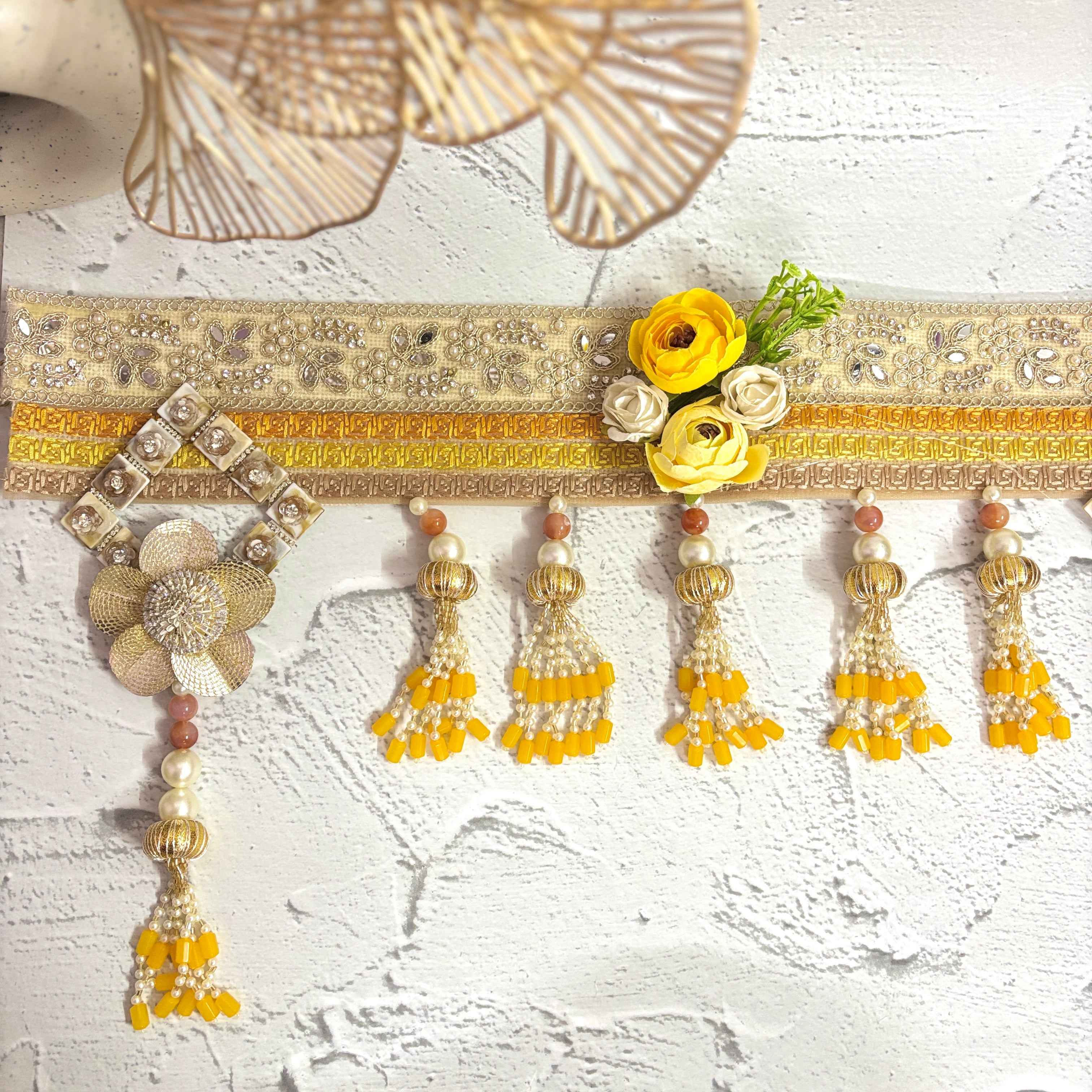 Close-up of the Marigold Majesty golden bandarwal, highlighting the intricate beaded tassels, metal floral accents, and yellow flowers.