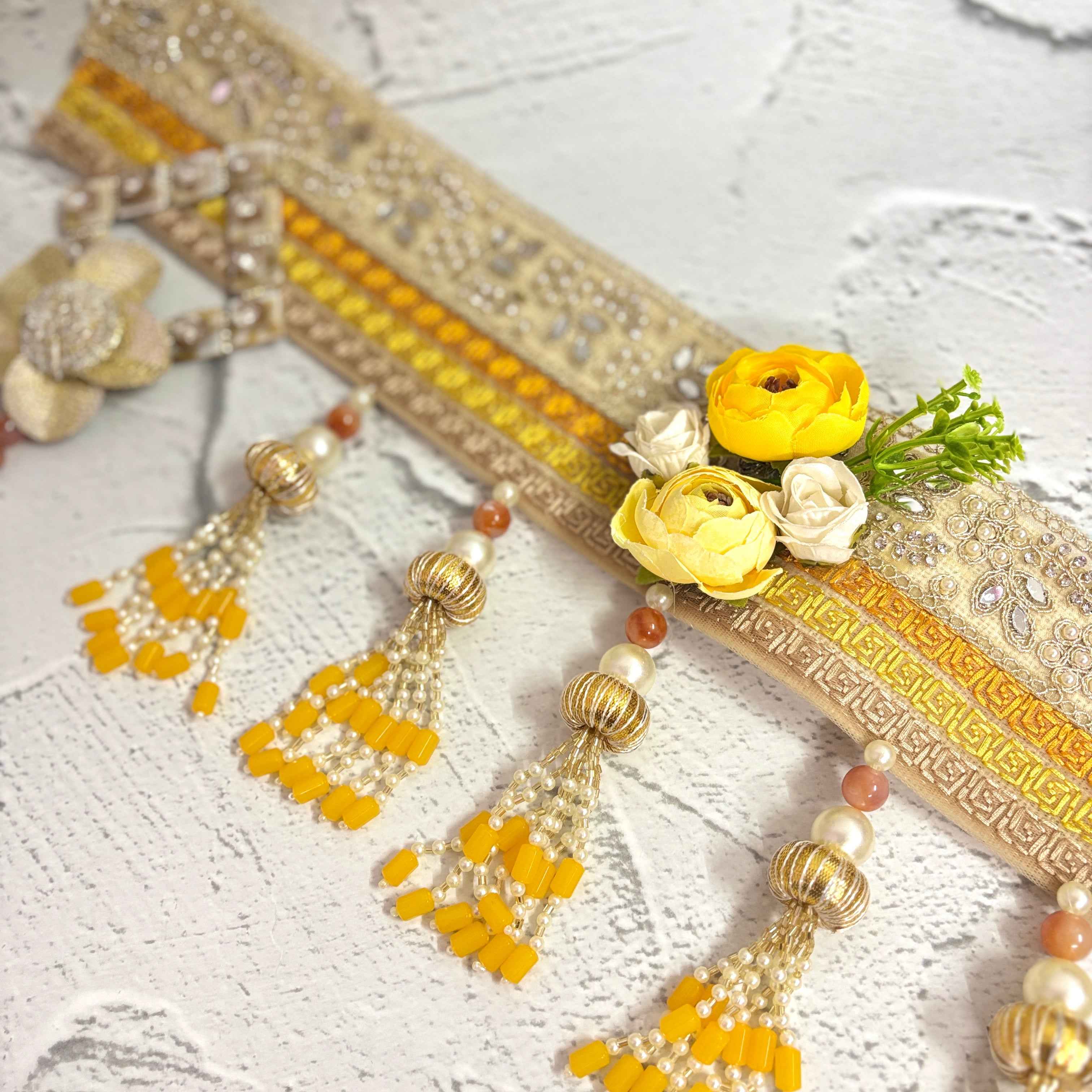 Close-up of the Marigold Majesty golden bandarwal, highlighting the intricate beaded tassels, metal floral accents, and yellow flowers.