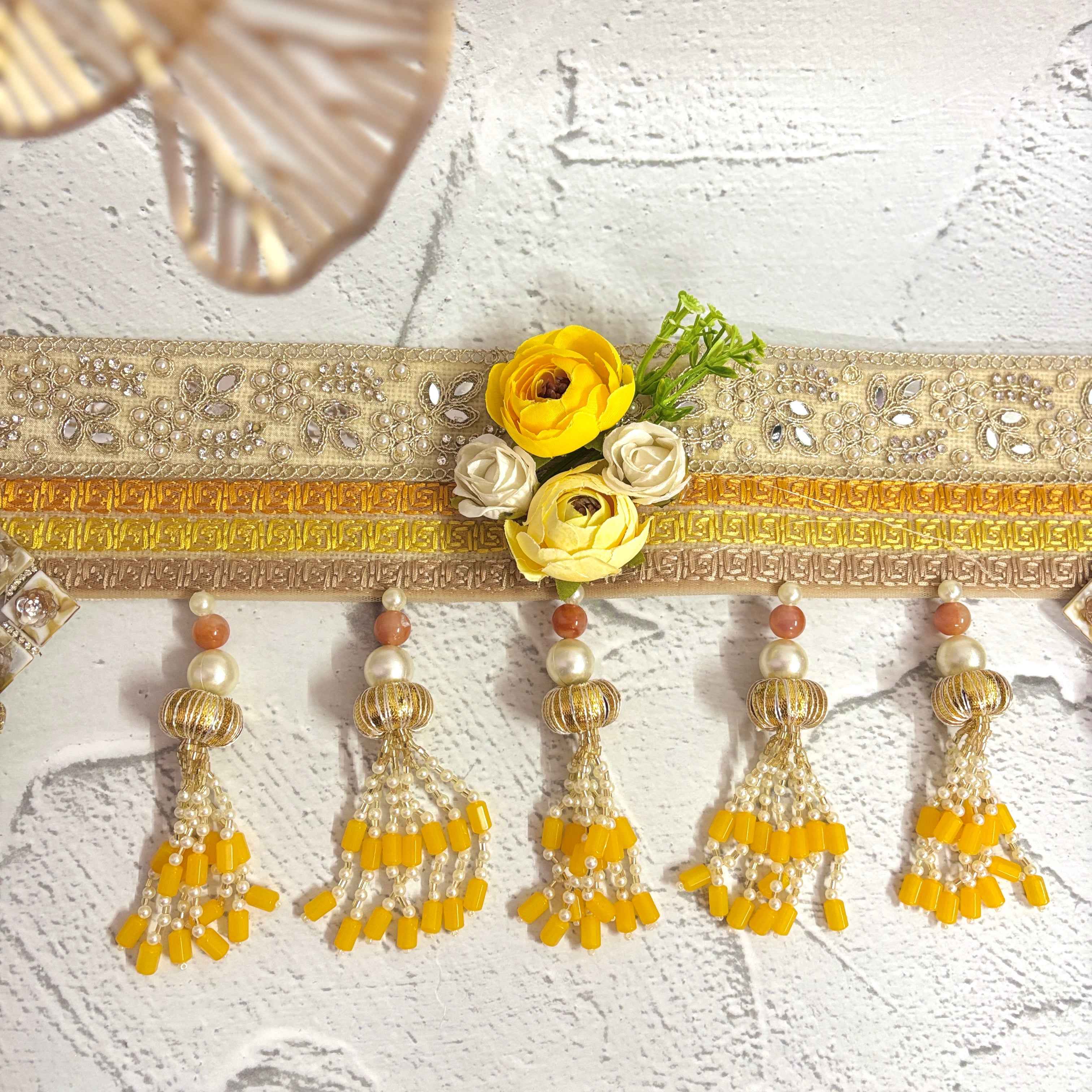Close-up of the Marigold Majesty golden bandarwal, highlighting the intricate beaded tassels, metal floral accents, and yellow flowers.