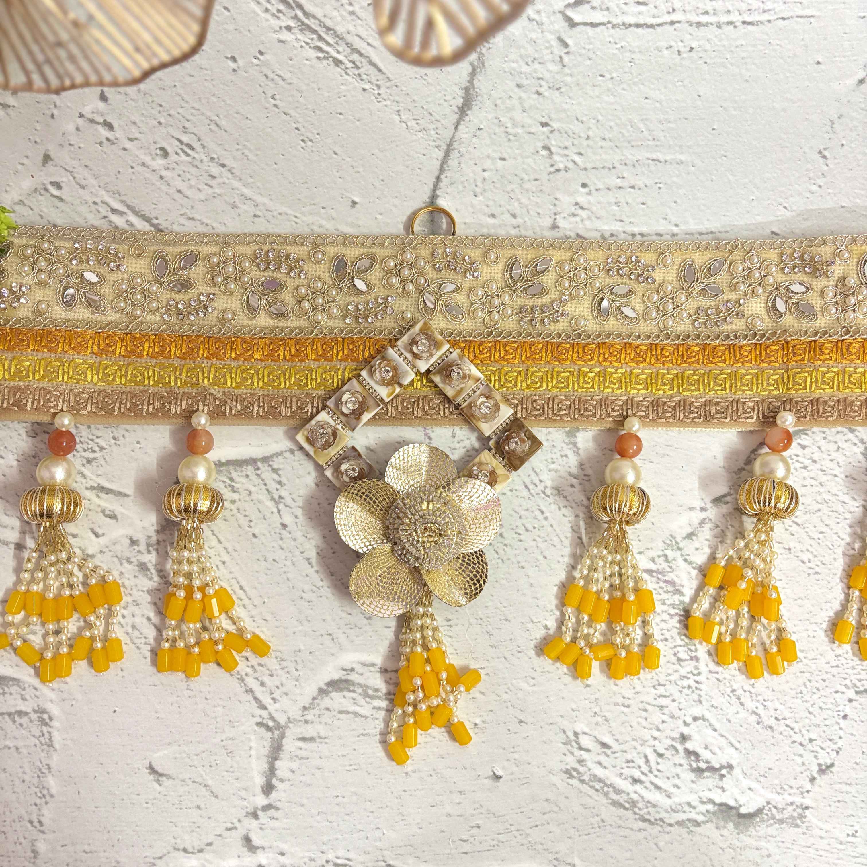 Close-up of the Marigold Majesty golden bandarwal, highlighting the intricate beaded tassels, metal floral accents, and yellow flowers.
