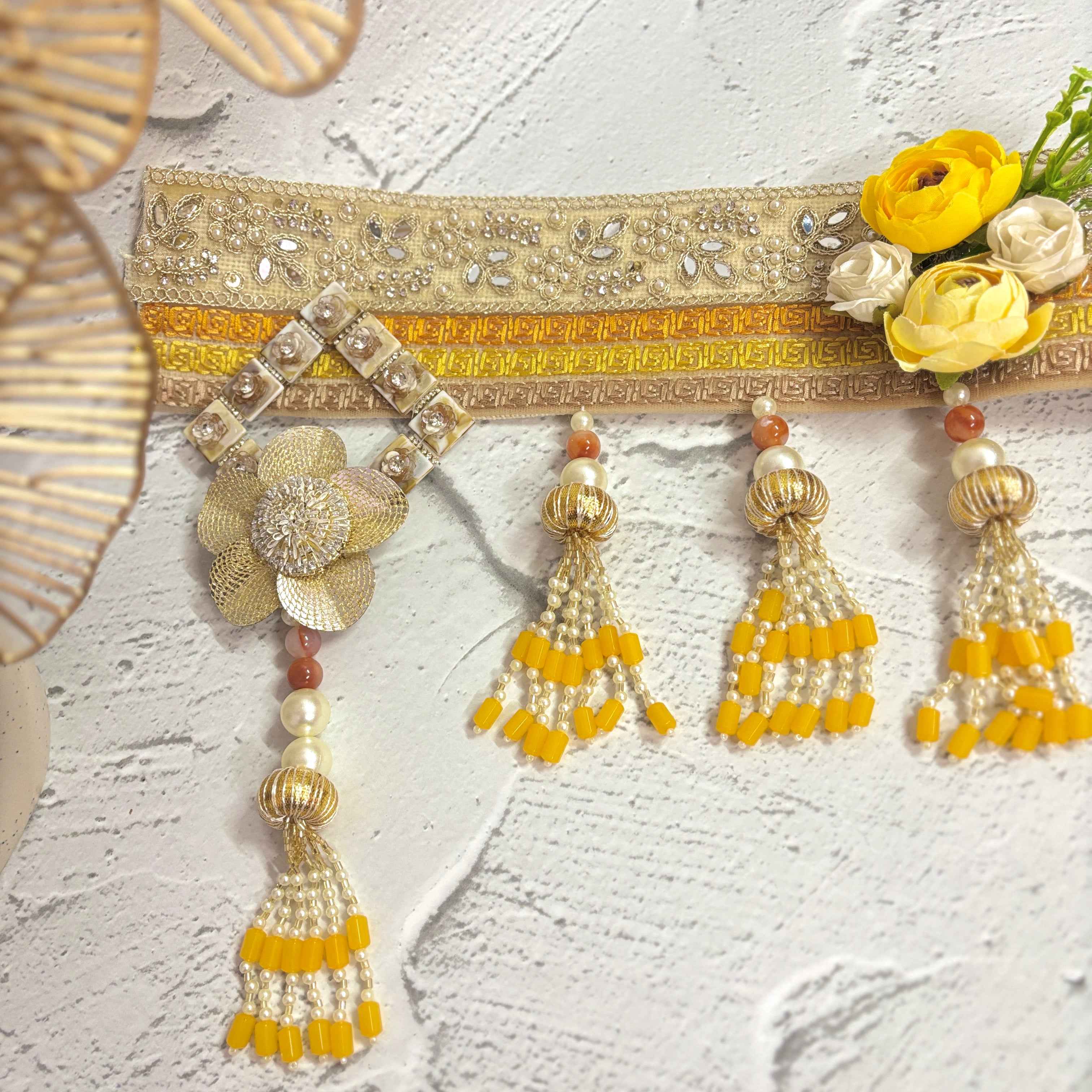 Close-up of the Marigold Majesty golden bandarwal, highlighting the intricate beaded tassels, metal floral accents, and yellow flowers.
