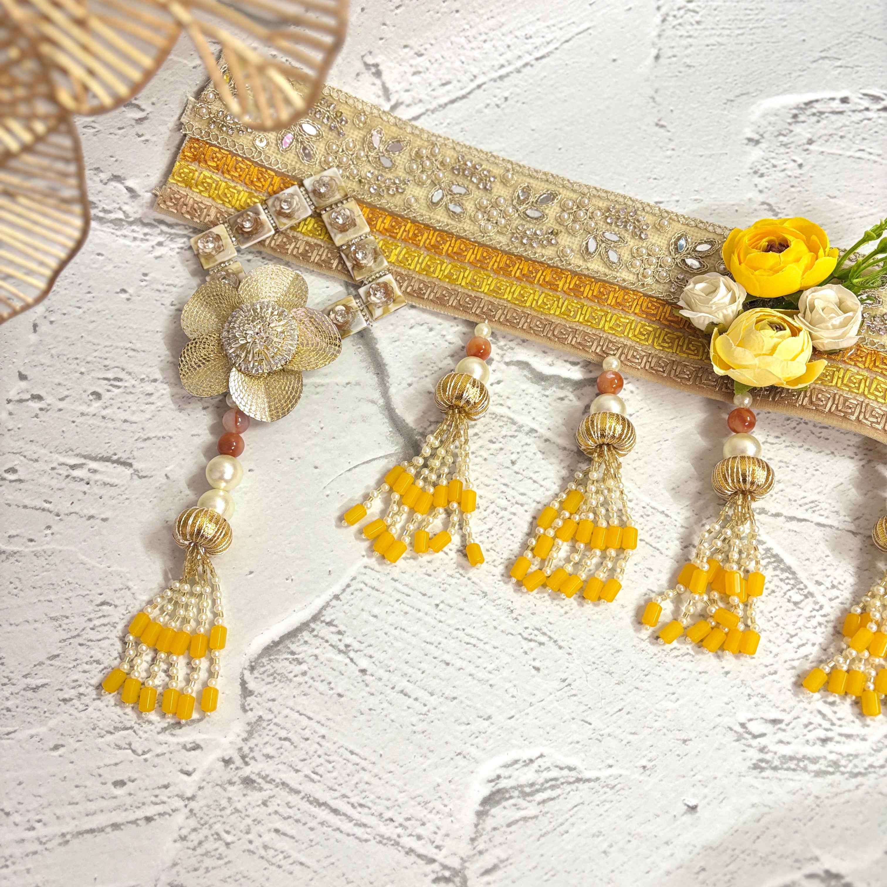 Close-up of the Marigold Majesty golden bandarwal, highlighting the intricate beaded tassels, metal floral accents, and yellow flowers.