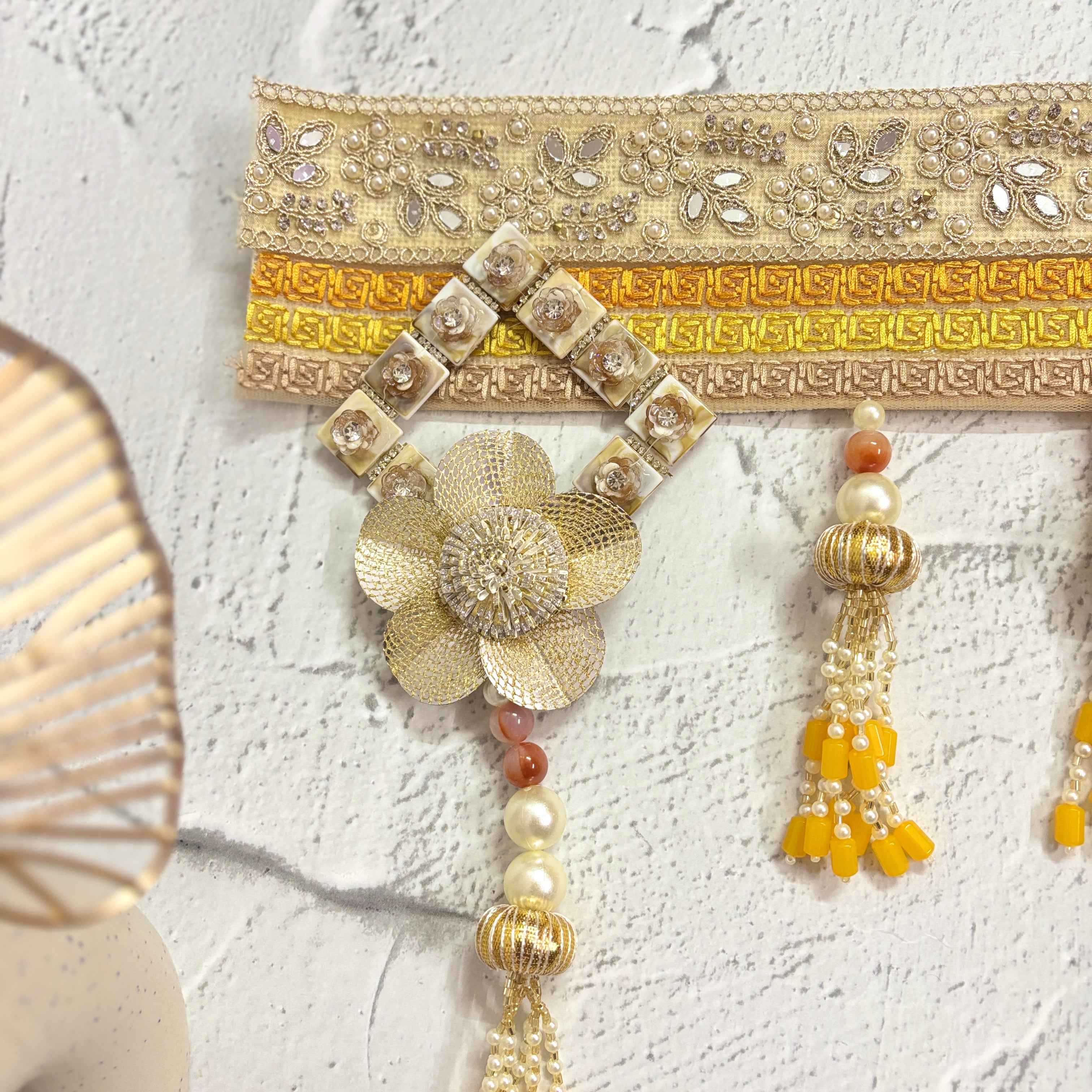 Close-up of the Marigold Majesty golden bandarwal, highlighting the intricate beaded tassels, metal floral accents, and yellow flowers.