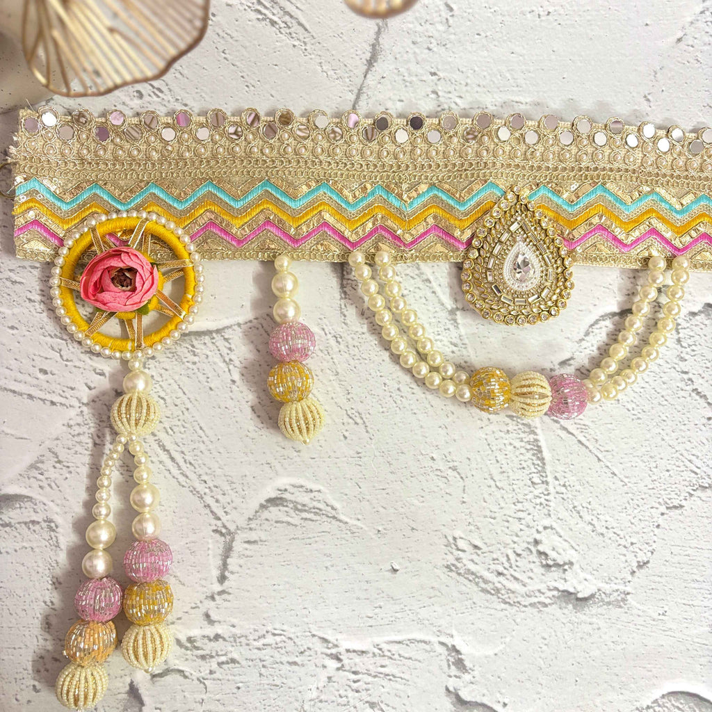 Close-up of the Utsav Leher handmade bandarwal with a gold, pink, yellow, and blue zigzag design. The image highlights the intricate mirror work, pearls, and beaded tassels