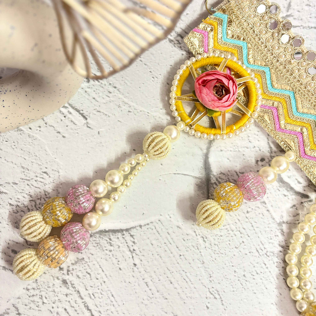 Close-up of the Utsav Leher handmade bandarwal with a gold, pink, yellow, and blue zigzag design. The image highlights the intricate mirror work, pearls, and beaded tassels